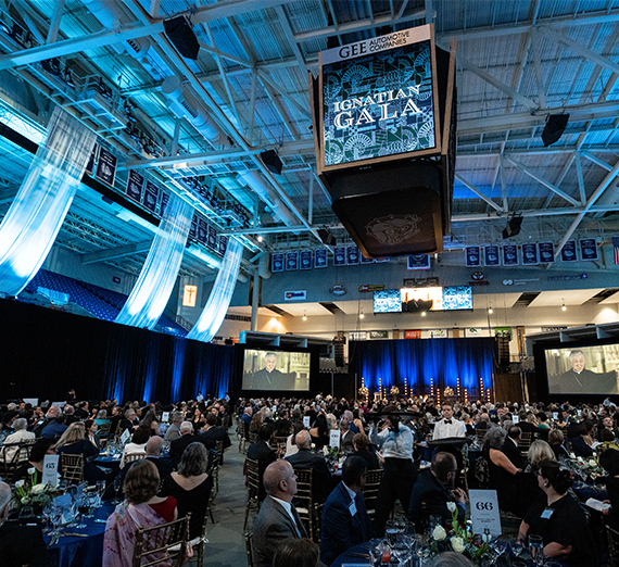 Un homme en tenue de remise des diplômes lève son diplôme sur lequel est écrit « Gonzaga University »